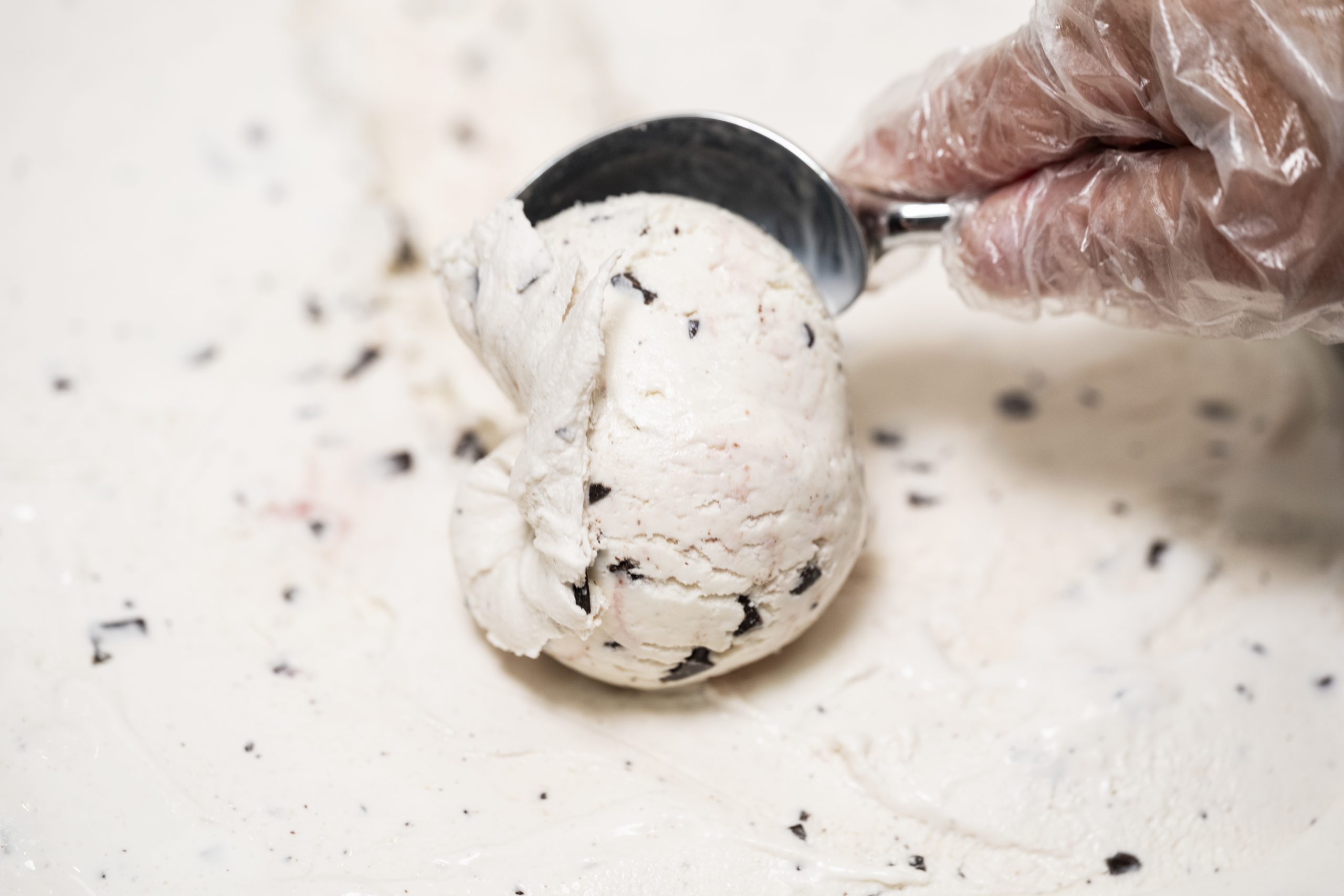 Vanilla-flavored ice cream with chocolate chips and a raspberry swirl is being scooped.