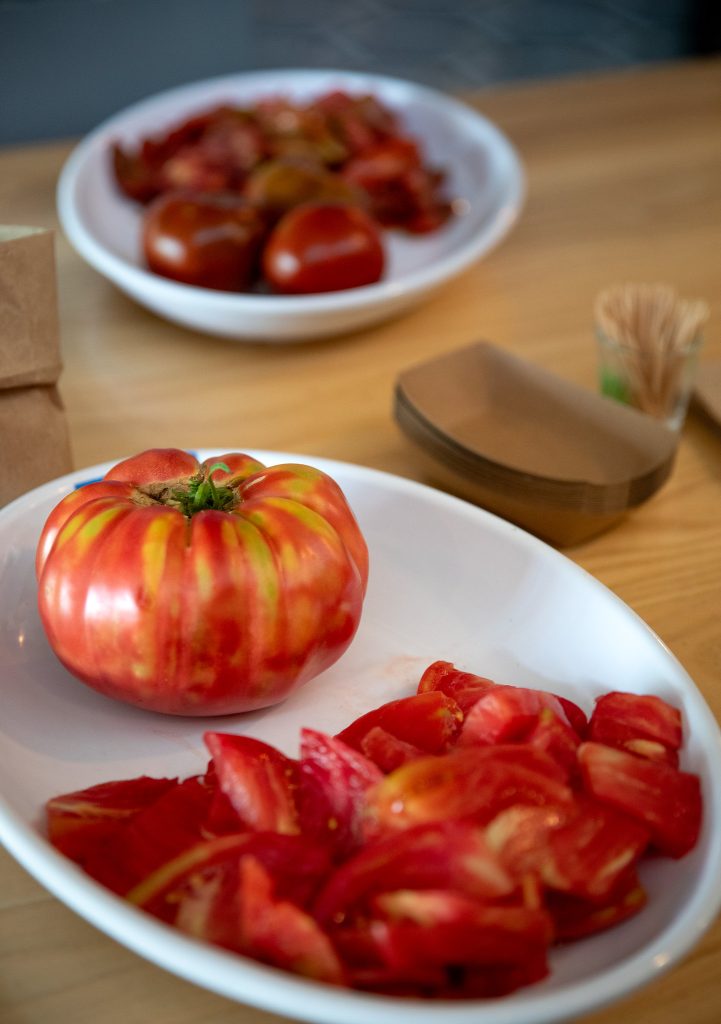plate of a whole tomato and sliced tomatoes
