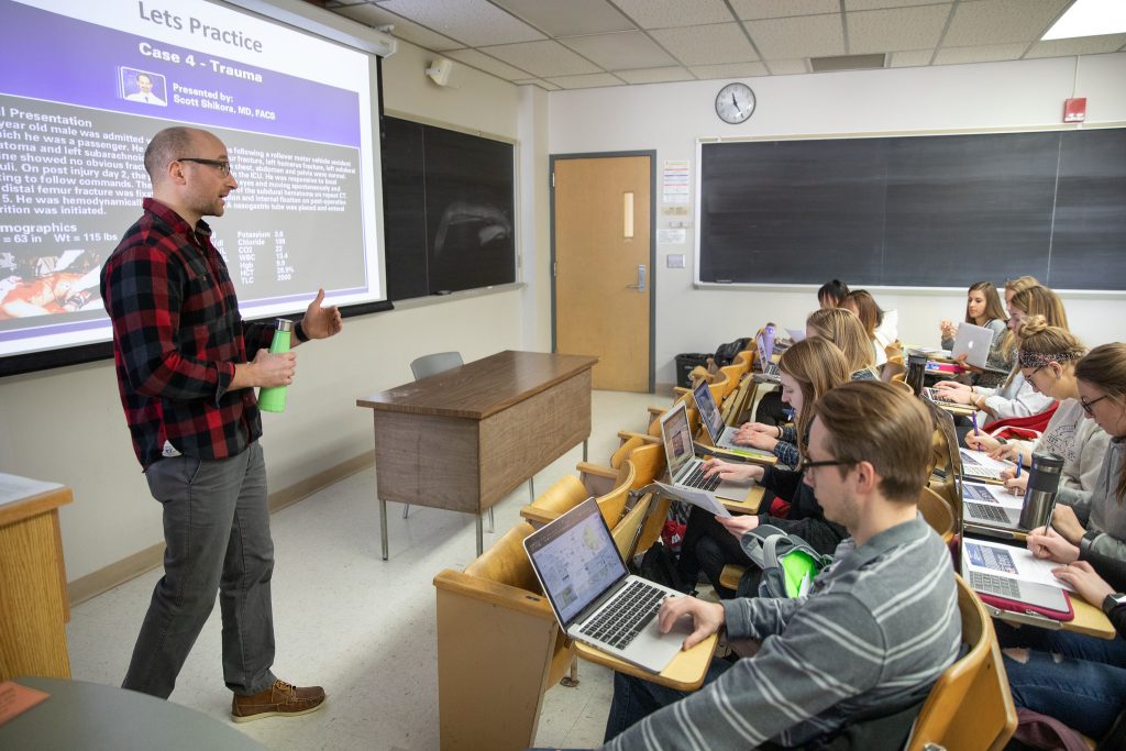 A person is standing at the front of a classroom teaching to a group of students