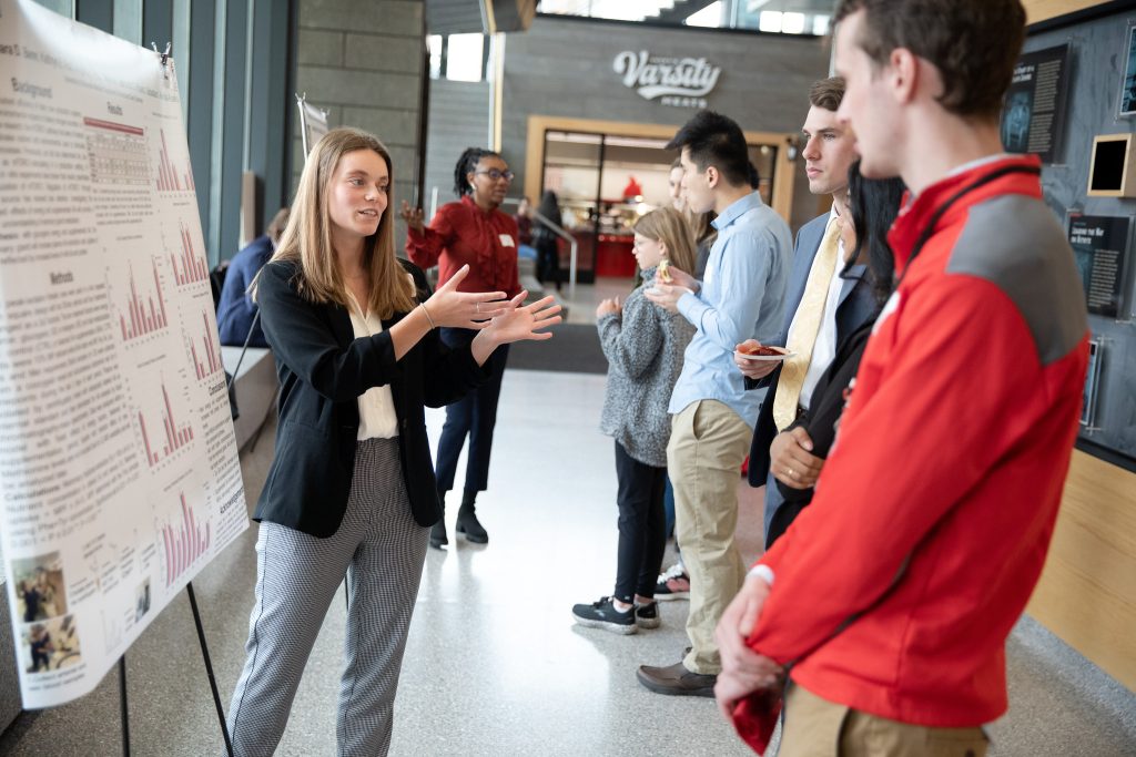 A student presents a research poster to other students