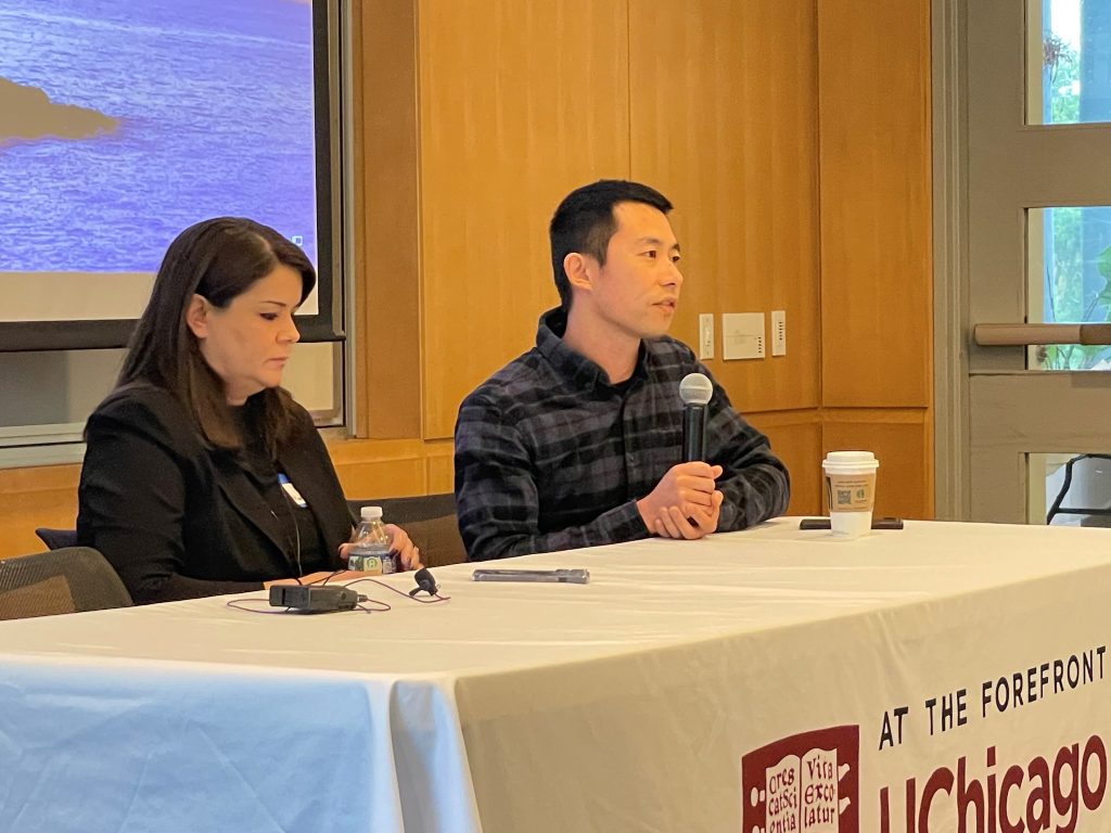 Two people sit behind a clothed table, at the front of a classroom, discussing career development.