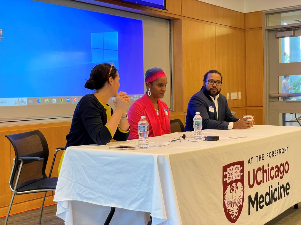 Three people sitting behind a clothed table that says "At the Forefront; UChicago Medicine."
