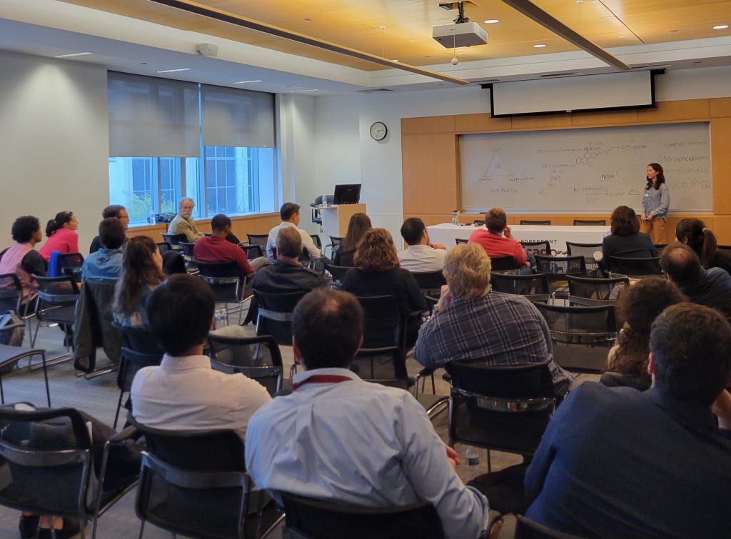 Woman standing in front of classroom explaining her research to a group of people seated.